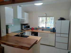a kitchen with white cabinets and a wooden counter top at LOG-INN Hakuba in Hakuba
