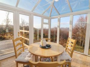 a conservatory with a table and chairs and windows at Doire An Daimh in Acharacle