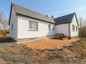 a white house with a bench in front of it at Doire An Daimh in Acharacle