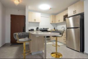 a kitchen with a stainless steel refrigerator and two bar stools at Luxury suites 2 in Kingston