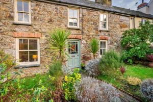 an old stone house with a green door in a garden at Finest Retreats - Wallis Cottage in Fishguard