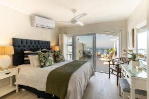 a bedroom with a bed with a desk and a balcony at Beachfront Apartments Shakas Rock - Skiathos, Pool, Ocean Views in Ballito