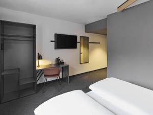 a room with a bed and a desk with a television at B&B HOTEL Lippstadt in Lippstadt +18 photos