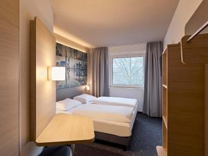 a hotel room with two beds and a window at B&B HOTEL Lippstadt in Lippstadt