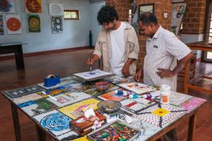 two men standing around a table with art on it at SwaSwara Wellness - A CGH Earth Experience, Gokarna in Gokarna +204 photos
