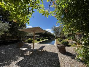 a bench and an umbrella next to a pool at Le Mas de Béthel in Gordes