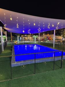 a swimming pool lit up at night with lights at Private farm Pool games Ras alkhaimah in Maghribīyah +67 photos