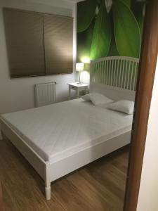 a bedroom with a large white bed with a green wall at Apartament U Sternika in Międzyzdroje