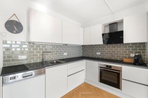 a kitchen with white cabinets and a clock on the wall at Zentral und Ruhig am Park - 2BR - gratis Parken - 2 Balkone in Graz