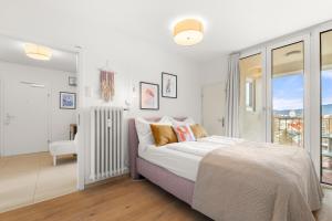 a white bedroom with a bed and a window at Zentral und Ruhig am Park - 2BR - gratis Parken - 2 Balkone in Graz