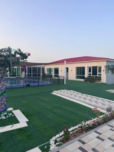 a building with a green yard with a building at Private farm Pool games Ras alkhaimah in Maghribīyah