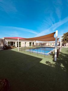 a swimming pool with a hammock over it next to a building at Private farm Pool games Ras alkhaimah in Maghribīyah