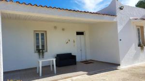 a white house with a black chair and a table at Villetta della Pace nel cuore del Salento in Torre Santa Susanna
