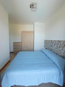 a bedroom with a bed with a blue bedspread at Belmonte Holiday Apartment in Brezzo +15 photos