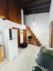 a kitchen with a white refrigerator and a staircase at Loft 2 quartos with full kitchen in Uruçuca