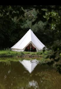 a white tent sitting next to a body of water at Wildberry glamping in Orgères-la-Roche