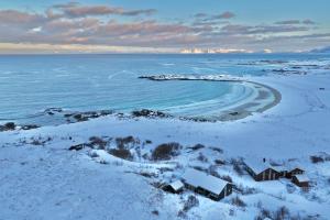a house on the shore of a beach in the snow at Lofoten Links Lodges in Gimsøy