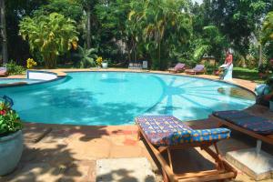 a swimming pool with two chairs and a woman standing next to it at Garden Level Studio in Mtwapa