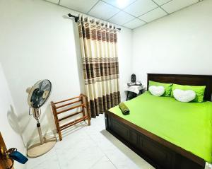 a bedroom with a green bed and a fan at D2 Holiday Inn in Badulla