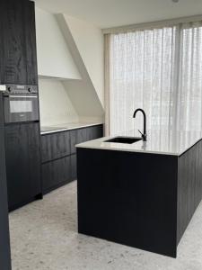 a kitchen with a black island with a sink at The Corner -FRANS in Beernem