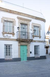 a white building with a green door and a balcony at La Posada de Zepeda in Jerez de la Frontera