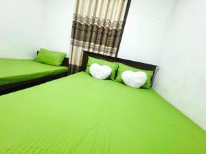 two beds in a room with green sheets and pillows at D2 Holiday Inn in Badulla +7 photos