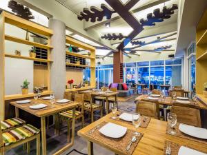 um restaurante com mesas e cadeiras de madeira e uma grande janela em Atelier Suites em Bangkok