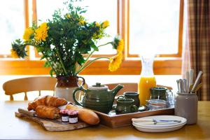a table with a tray of bread and a vase with flowers at Knapp Cottage in Charlbury