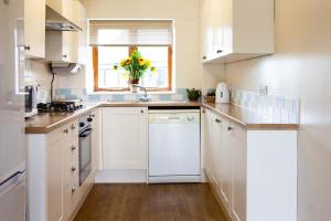 a kitchen with white cabinets and a vase of flowers at Knapp Cottage in Charlbury