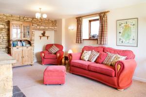 a living room with a red couch and two chairs at Knapp Cottage in Charlbury +23 photos