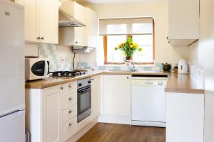 a kitchen with white cabinets and a vase of flowers at Knapp Cottage in Charlbury