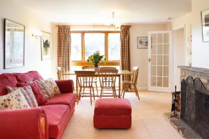 a living room with a red couch and a table at Knapp Cottage in Charlbury