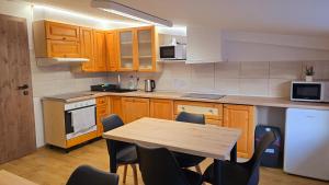 a kitchen with wooden cabinets and a table with chairs at Penzion DRUCKER in Čadca