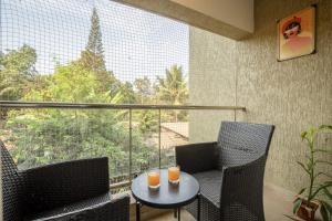 a balcony with two chairs and a table with orange candles at Charvi Reemz Anjuna in Anjuna