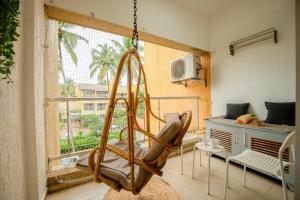 a swinging chair in a room with a window at Charvi Reemz Anjuna in Anjuna