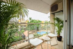 a balcony with two chairs and a view of a pool at Charvi Reemz Anjuna in Anjuna