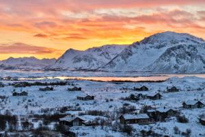 a snowy village with a mountain in the background at Lofoten Links Lodges in Gimsøy