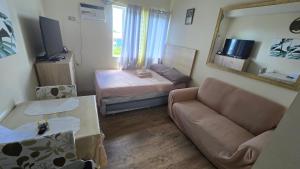 a living room with a couch and a bed and a mirror at The Cozy Place Stanford 2 in Silang