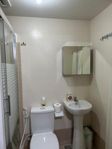 a white bathroom with a toilet and a sink at The Cozy Place Stanford 2 in Silang