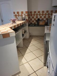 a kitchen with a refrigerator and a tiled floor at entre arènes et maison carrée in Nîmes