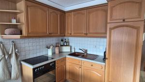 a kitchen with wooden cabinets and a sink at Summit & Spring Studio - Leukerbad in Leukerbad