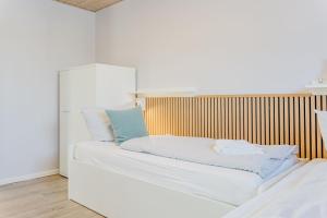 a white bed with a blue pillow on it at Büdlfarm - Der Familien-Erlebnishof in Strandnähe in Fehmarn