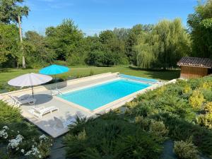 a swimming pool with an umbrella and two chairs at SALVEO Suites in Loubens +17 photos
