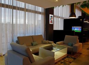 a living room with a couch and chairs and a tv at ibis Styles Maracanau in Maracanaú