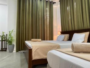 two beds in a hotel room with green curtains at Sea Path Villa - Dikwella in Dickwella