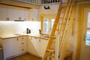 a kitchen with white cabinets and a wooden ladder at Magical Wellness Cottage Trvalka in Křimov