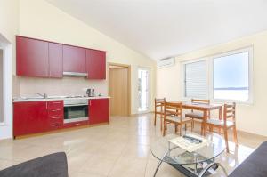 a kitchen with red cabinets and a table and chairs at Apartments Seaview in Tučepi +57 photos