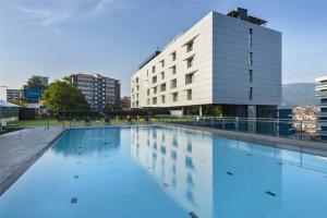 a large swimming pool in front of a building at Occidental Bilbao in Bilbao