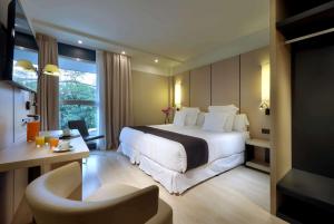 a hotel room with a large bed and a chair at Occidental Bilbao in Bilbao