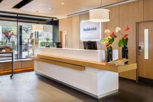 a lobby with a reception counter with flowers in vases at Occidental Bilbao in Bilbao +75 photos